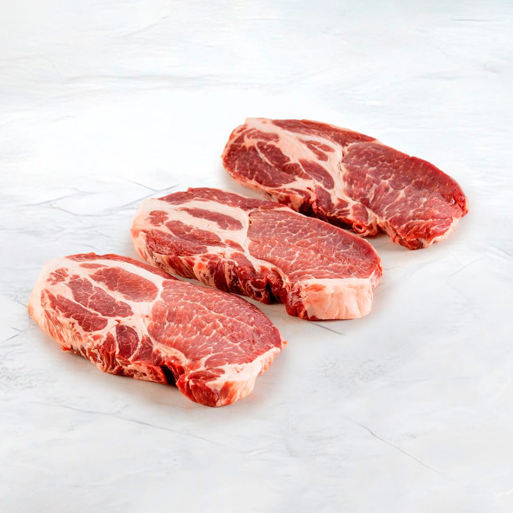 tre fette di capocollo di maiale su fondo marmo