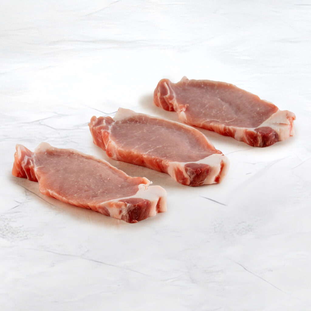 foto di tre fette di lonza di maiale su fondo ardesia